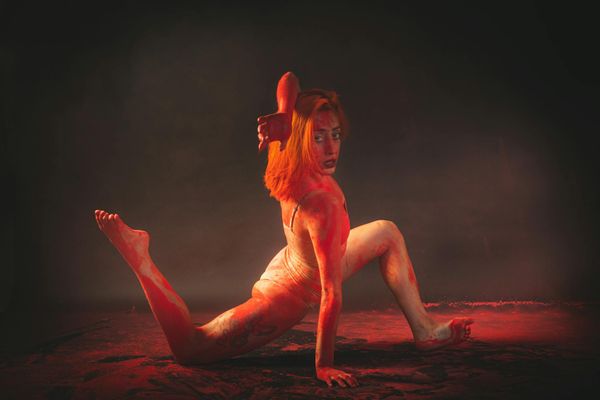 Woman performing a fluid yoga transition in a dark studio.